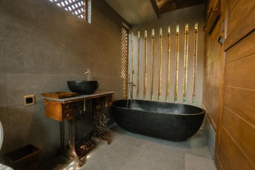 a bathroom with a black tub and a sink at Chandaka Borobudur in Magelang