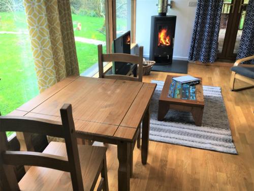 a living room with a wooden table and a fireplace at Jopes Mill and Lodge in Looe