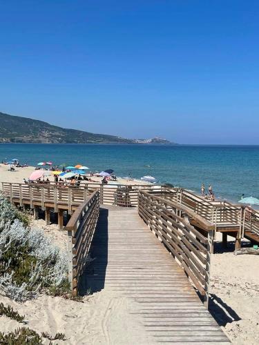 a wooden boardwalk leading to a beach with umbrellas at Casa Mac in La Ciaccia