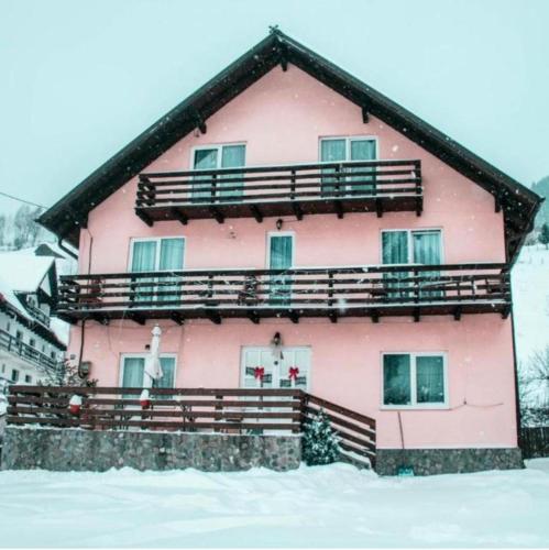 a pink house with snow in front of it at Casa Anastasia - Moieciu de Sus in Moieciu de Sus