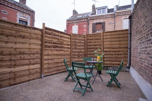 un patio con una valla, una mesa y sillas en Gite Amiens en Amiens