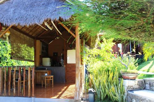 een veranda van een huis met een rieten dak bij Bamboo Bungalow Jungle View in Nusa Penida