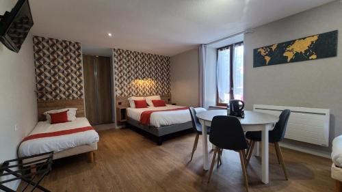 um quarto de hotel com duas camas e uma mesa e cadeiras em Logis Hôtel Auberge de l'Allagnonette em Saint-Poncy