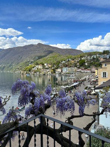 a town with purple flowering trees on a body of water at Appartamento Ascona Vista Lago in Ascona