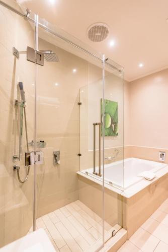 a bathroom with a shower and a tub and a sink at Gold Reef City Theme Park Hotel in Johannesburg