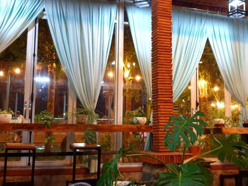 um restaurante com cortinas brancas e vasos de plantas em Boss cà phê & Homestay Nguyên căn em Chi Lăng