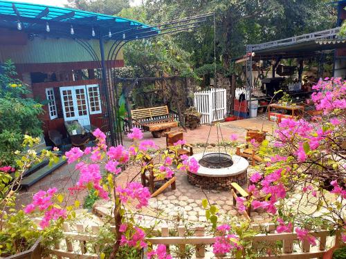 un jardin avec un foyer extérieur et des fleurs roses dans l'établissement Boss cà phê & Homestay Nguyên căn, à Chi Lăng