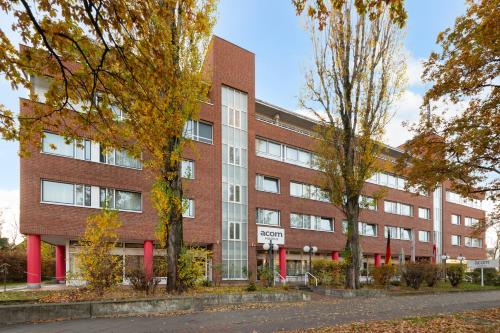 een rood bakstenen gebouw met bomen ervoor bij acom Hotel Berlin City Sued in Berlijn