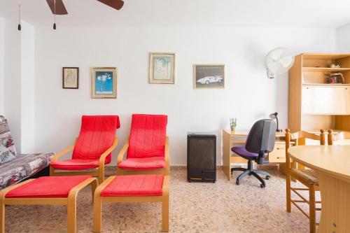 a living room with red chairs and a table at Edificio Flamingo in Gandía