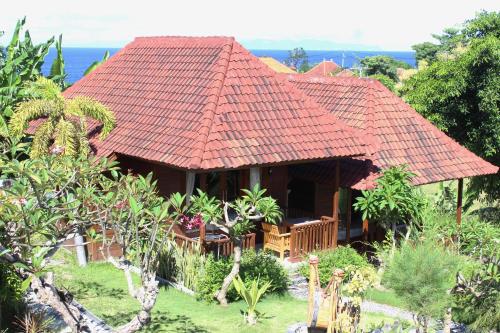 a house with a red roof with a garden at Bamboo Bungalow Jungle View in Nusa Penida