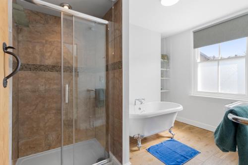 a bathroom with a shower and a tub and a sink at Exe Riverside Retreat Holiday Home in Exeter