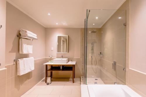 uma casa de banho com um chuveiro, um lavatório e uma banheira em Gold Reef City Theme Park Hotel em Joanesburgo
