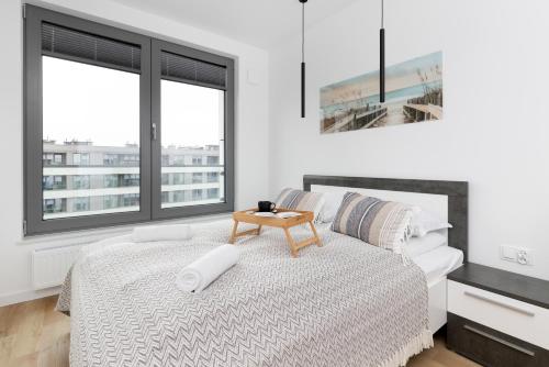 a white bedroom with a bed with a table on it at Plac Unii Apartment Gdynia by Renters in Gdynia