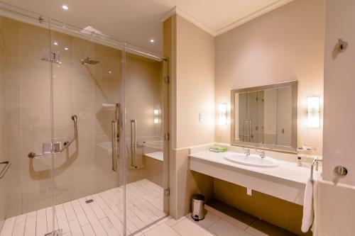 a bathroom with a shower and a sink and a tub at Gold Reef City Theme Park Hotel in Johannesburg