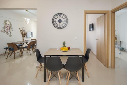 uma sala de jantar com mesa e cadeiras e um relógio em Downtown Guesthouse by Estia em Heraclião