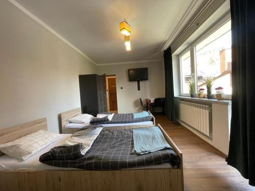 two beds in a room with a large window at Apartament Ogrodowa in Muszyna