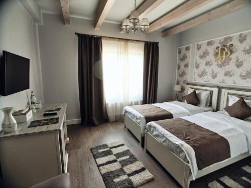 a bedroom with two beds and a desk and a television at Domeniile Panciu Winery & Resort in Sîrbi