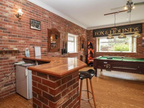 a brick walled kitchen with a bar and a pool table at Walnut House in Lowestoft