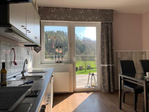 a kitchen with a large window with a view of a yard at Hof Görrespesch-Ferien im Herzen der Schneifel in Schlausenbach