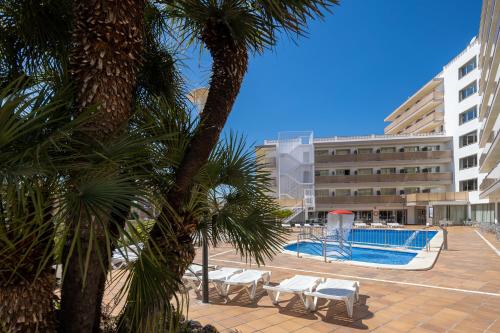 a resort with a pool and palm trees and a building at htop Royal Star & SPA #htopFun in Lloret de Mar