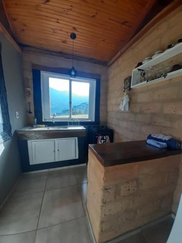 uma cozinha com um lavatório e uma janela num quarto em Cabana do Camelo em São Bento do Sapucaí