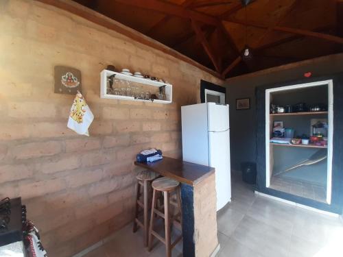 una cucina con frigorifero, tavolo e sgabello di Cabana do Camelo a São Bento do Sapucaí