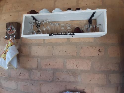 a shelf on a brick wall with glasses on it at Cabana do Camelo in São Bento do Sapucaí
