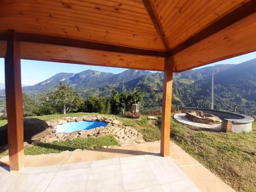 a pavilion with a pool and mountains in the background at Cabana do Camelo in São Bento do Sapucaí