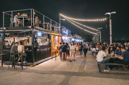 una folla di persone sedute ai tavoli in una strada di notte di OrigInn Space a Taipei