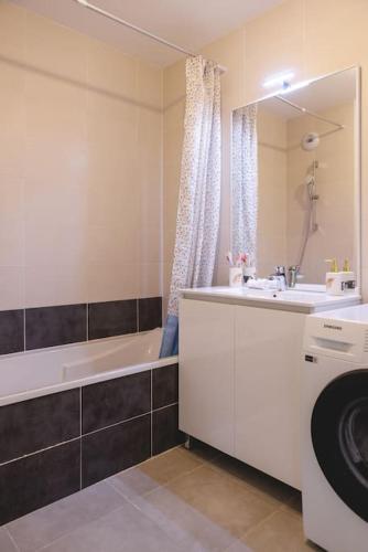 La salle de bains est pourvue d'une baignoire, d'un lavabo et d'un lave-linge. dans l'établissement Superbe appartement 2 chambres - parking gratuit, à Bourg-en-Bresse