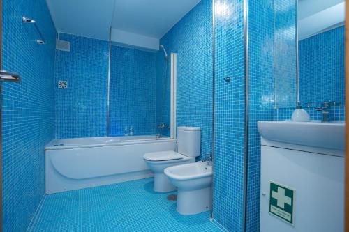 Baño de azulejos azules con aseo y lavamanos en Alta Guesthouse, en Coímbra