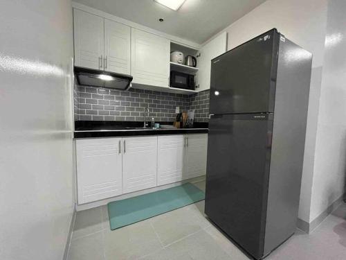 a kitchen with white cabinets and a black refrigerator at One Bedroom Condo Subic Bay in Morong