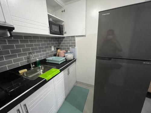 a kitchen with a sink and a black refrigerator at One Bedroom Condo Subic Bay in Morong