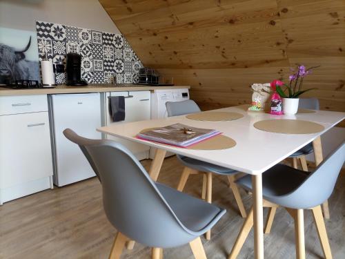 - une cuisine avec une table et des chaises blanches dans l'établissement Gîte l'estive du Clozel, à Besse-en-Chandesse