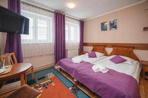 a bedroom with two beds and a table and a tv at Wanta in Zakopane