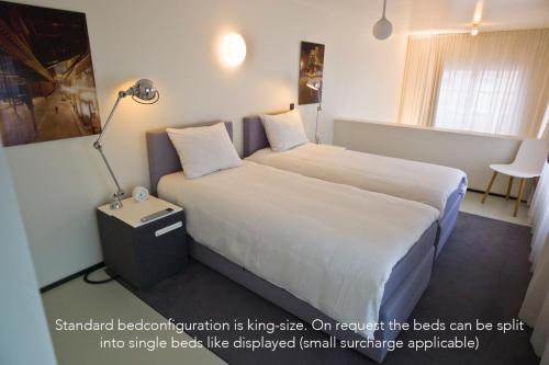 a hotel room with two beds and a lamp at Urban Residences Maastricht in Maastricht