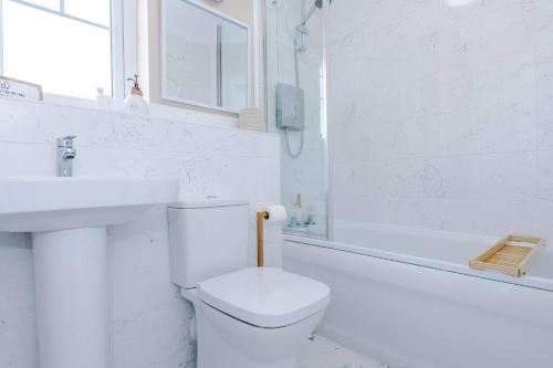 a white bathroom with a toilet and a sink at Full SKY TV Access 2BR Stylish Apartment in Hough Green
