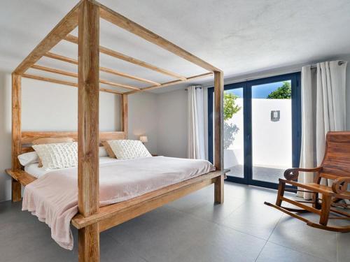 a bedroom with a wooden canopy bed and a chair at Modern Villa with sea views in Sant Josep de sa Talaia