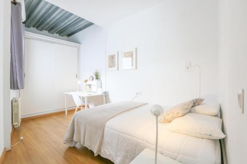 um quarto branco com uma cama e uma secretária em Mata 16 em Sevilha