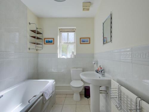 a white bathroom with a tub and a toilet and a sink at Pass the Keys Spacious apartment for 2 free parking in Manchester