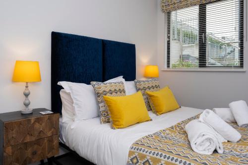 a bedroom with a large bed with yellow and white pillows at 2 Middlecombe - Luxury Apartment at Byron Woolacombe, only 4 minute walk to Woolacombe Beach! in Woolacombe