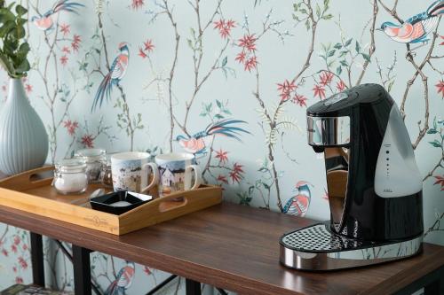 una macchinetta del caffè seduta su un tavolo di legno con tazze di Crookes House a Weston-super-Mare