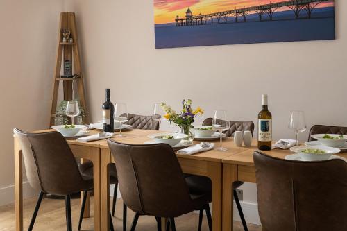 a wooden table with chairs and wine bottles on it at Crookes House in Weston-super-Mare