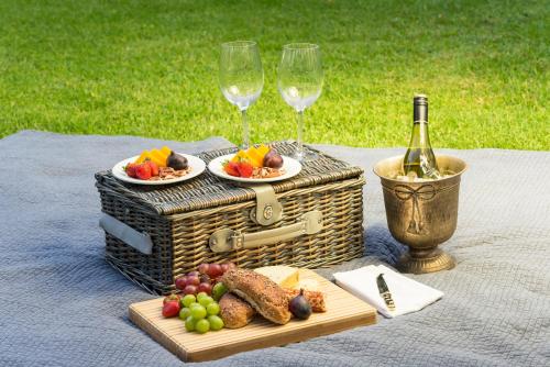 a picnic table with a basket of fruit and wine glasses at Malaga Hotel in Panorama