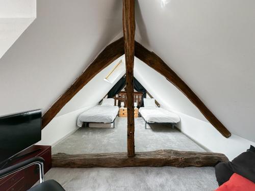 Cette chambre mansardée comprend 2 lits et une télévision. dans l'établissement W27B - Alla Prima, Super villa au cœur de Giverny, à Giverny