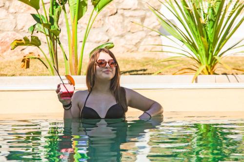 a woman in a swimming pool holding a drink at Delfinia Resort - All Inclusive in Kolymbia