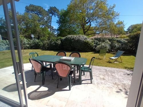 une table et des chaises vertes sur la terrasse dans l'établissement Pyla-sur-mer maison 2 chambres et jardin - à 400m des plages, à La Teste-de-Buch