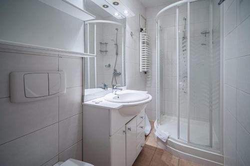 a white bathroom with a sink and a shower at Wanta in Zakopane