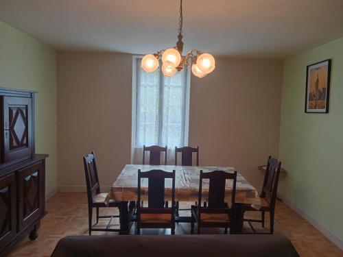une salle à manger avec une table, des chaises et un lustre dans l'établissement La Maison des Coteaux, à Meyrals