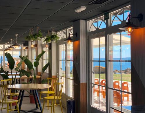 波布拉德卡拉米納爾的住宿－Kampaoh Ría de Arosa Playa，餐厅设有黄色的椅子和桌子以及窗户。